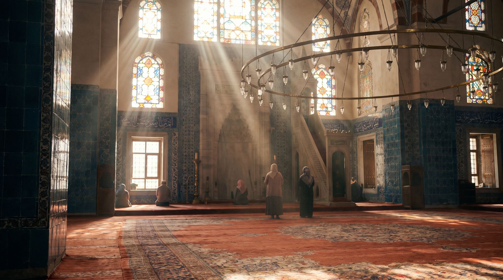 The serene interior of an Ottoman mosque with Iznik tiles and a ring of brass lamps